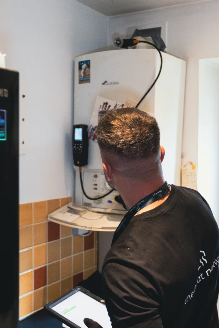 Boiler service vs gas safety check: what's the difference? 6 Engineer in black gloves tightening radiator connection during callout